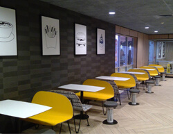 Indoor image of McDonalds with yellow benches and white tables.