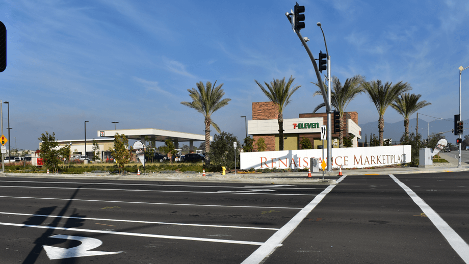 Outdoor image of 7-11 intersection showing palmtrees, streetlights, and a sign that reads 'Renaissance Marketplace'. 