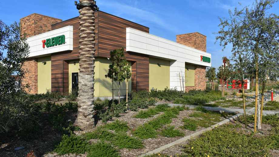 Outdoor image of 7-11 building back entrance with greenery in the foreground.