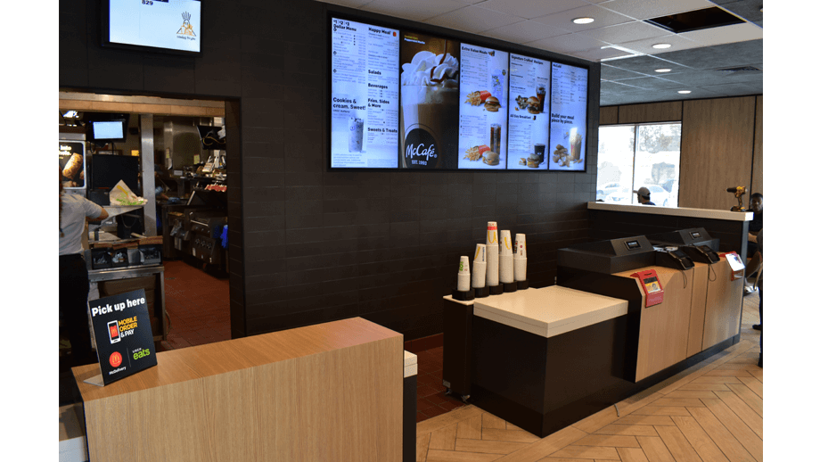 Indoor image of McDonalds showing the cashier area and menu screens.