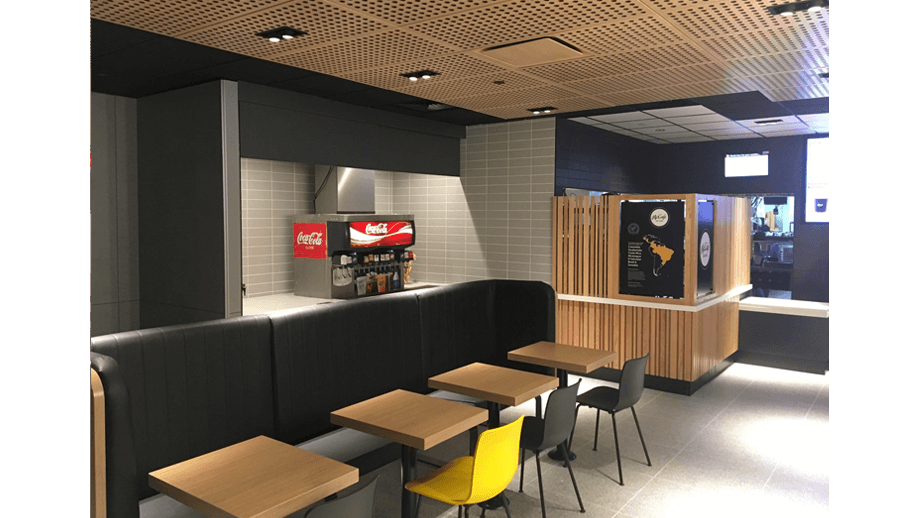 Indoor image of McDonalds showing dining area booths, chairs, and soda machine.